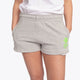Woman wearing the Osaka women shorts in grey with neon green logo. Front view