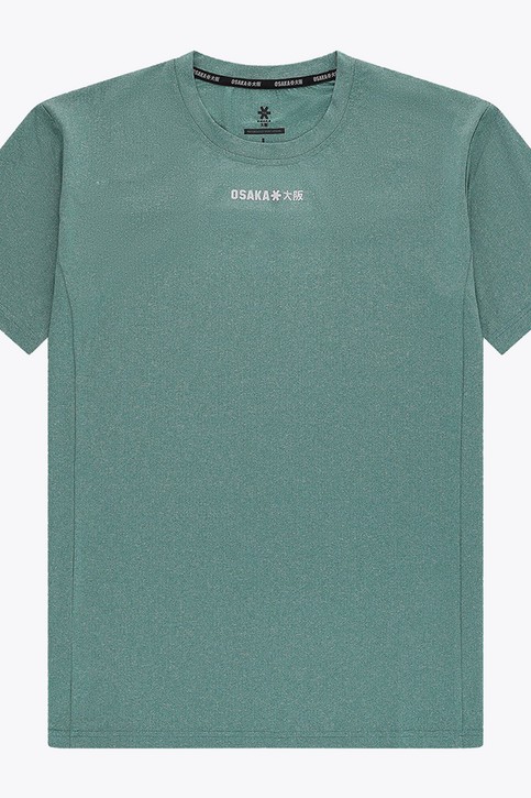 Osaka Men Apex Training Tee | Pineneedle Male model wearing Osaka Men’s Apex Training Tee in Pineneedle green with white training shorts, showcasing reflective chest logo and breathable athletic performance fabric.