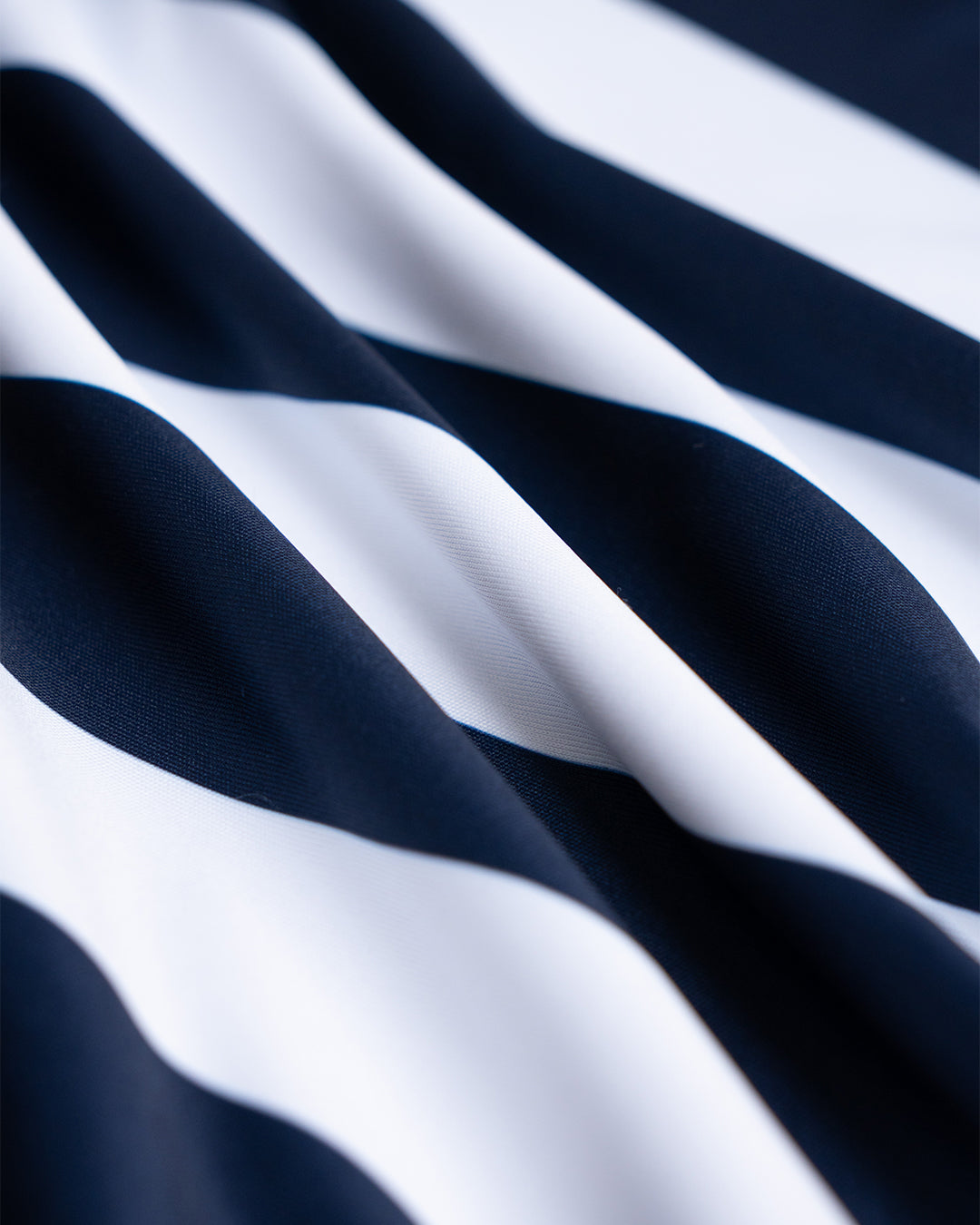 Close-up of Osaka custom teamwear polo collar and branded buttons on a navy and white striped sports jersey — premium kit construction detail