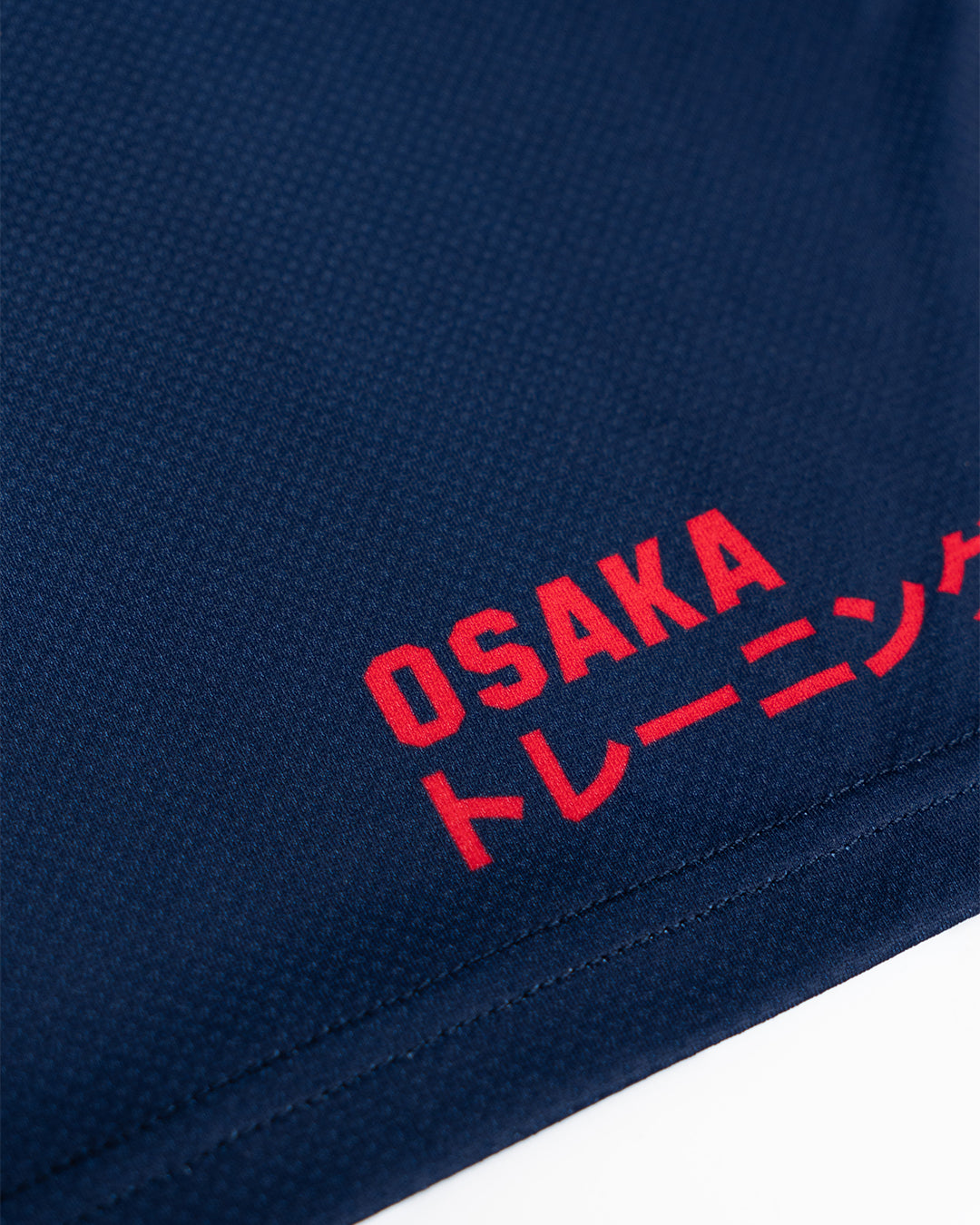 Close-up of Osaka custom teamwear polo collar and branded buttons on a navy and white striped sports jersey — premium kit construction detail