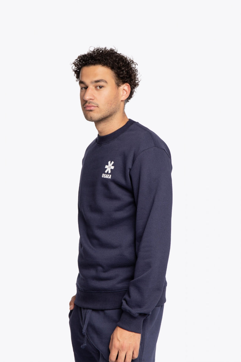 Man wearing the Osaka navy basic unisex sweater with logo in white. Side / front view