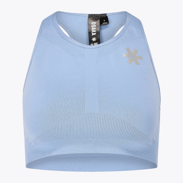 A light blue sleeveless athletic crop top with a ribbed neckline and hem, featuring a metallic silver geometric logo on the left chest. The brand name 'OSNA' is visible on the inner neck tag. #ManorBlue