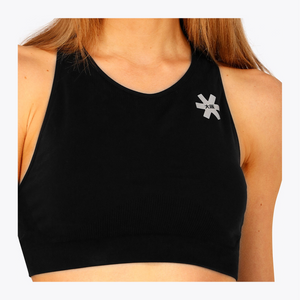A close-up of a woman wearing a black ribbed athletic crop top with a small white logo on the left chest, set against a plain white background. #FadedBlack