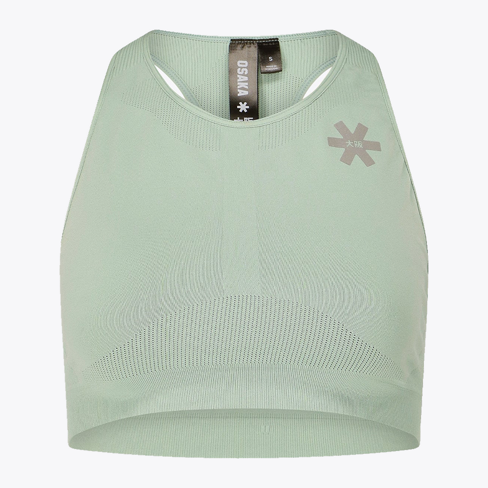 A pale sage green athletic crop top by OSMA, featuring a scoop neck, underwire cups, a textured knit pattern, and a gray logo on the left chest, displayed on a clean white background. #Jadeite