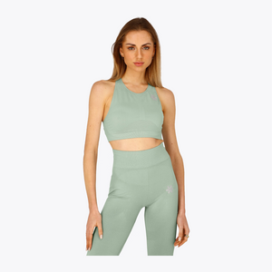 A woman modeling a matching sage green activewear set consisting of a sleeveless crop top and high-waisted leggings, set against a plain light gray background. #Jadeite