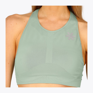 A woman wearing a sage green athletic sports bra with a textured knit pattern and a small gray logo on the upper chest, shown against a plain white background. #Jadeite