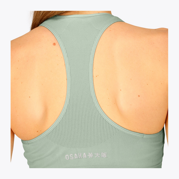 Back view of a woman wearing a sage green athletic racerback tank top with 'OSAKA' printed in white near the lower back, set against a plain white background. #Jadeite