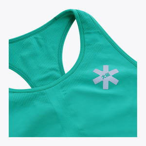 Close-up of a teal athletic top showing the racerback neckline and a white star-shaped logo with green characters on the chest, set against a light gray background. #BayouGreen
