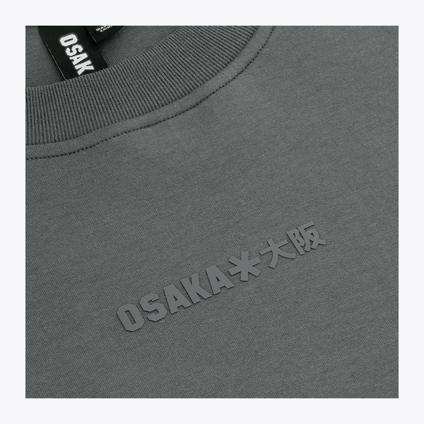 Unisex sweater close-up: dark grey melange knit, chest graphic logo, neck label #DarkGreyMelange