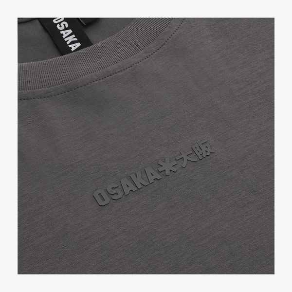 Close-up of a dark gray crewneck sweatshirt with embossed 'OSAKA**大阪' text on the chest and a black neck label reading 'OSAKA'. | Osaka World USA #DarkGrey