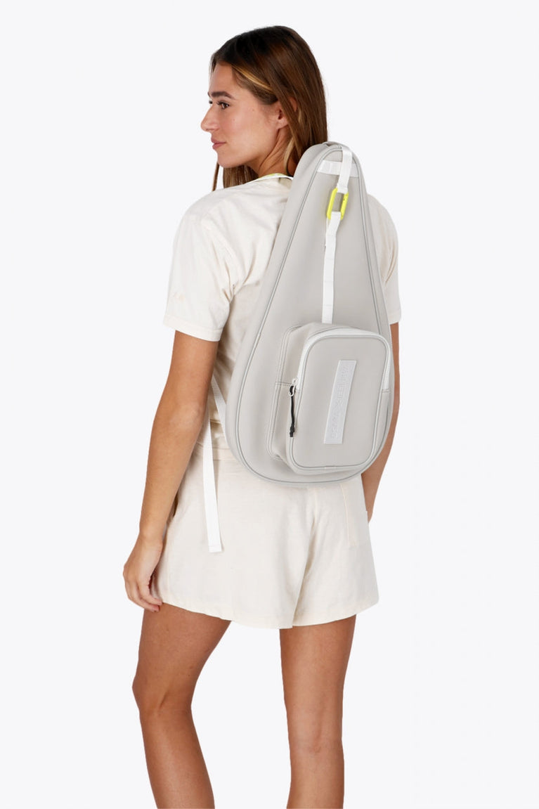 Osaka neoprene padel bag in light grey with logo in white. Woman wearing the bag