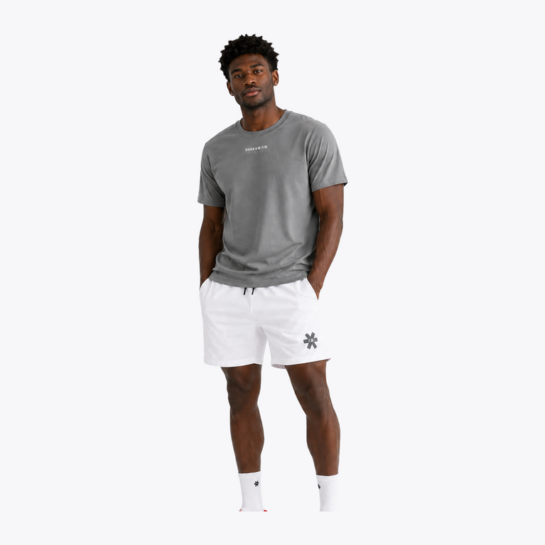 Black male model wearing Osaka Men’s Apex Training Tee in Quiet Gray and white training shorts, showcasing reflective chest branding, athletic fit, and breathable training fabric.