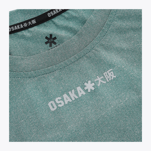 Close-up of the reflective Osaka Osaka logo printed across the upper chest of the Pineneedle green Apex Training Tee. #Pineneedle