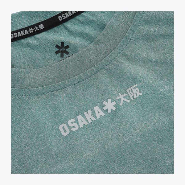Close-up of the reflective Osaka Osaka logo printed across the upper chest of the Pineneedle green Apex Training Tee. #Pineneedle