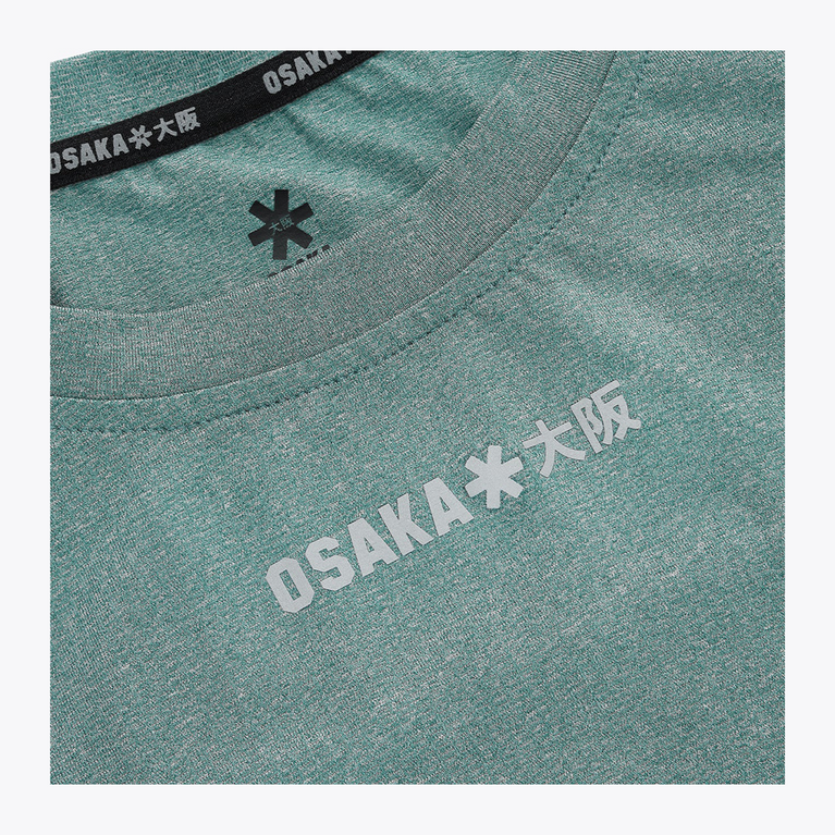 Close-up of the reflective Osaka Osaka logo printed across the upper chest of the Pineneedle green Apex Training Tee.