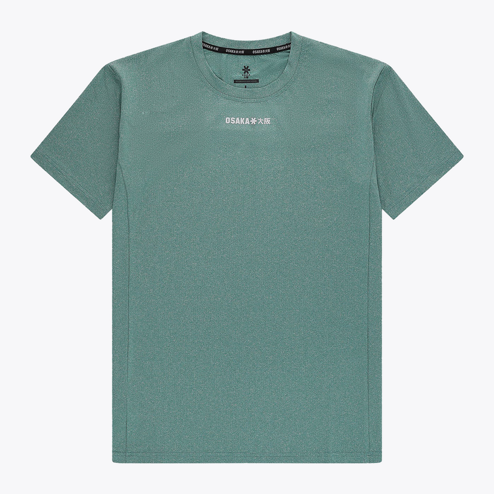 Male model wearing Osaka Men’s Apex Training Tee in Pineneedle green with white training shorts, showcasing reflective chest logo and breathable athletic performance fabric. #Pineneedle
