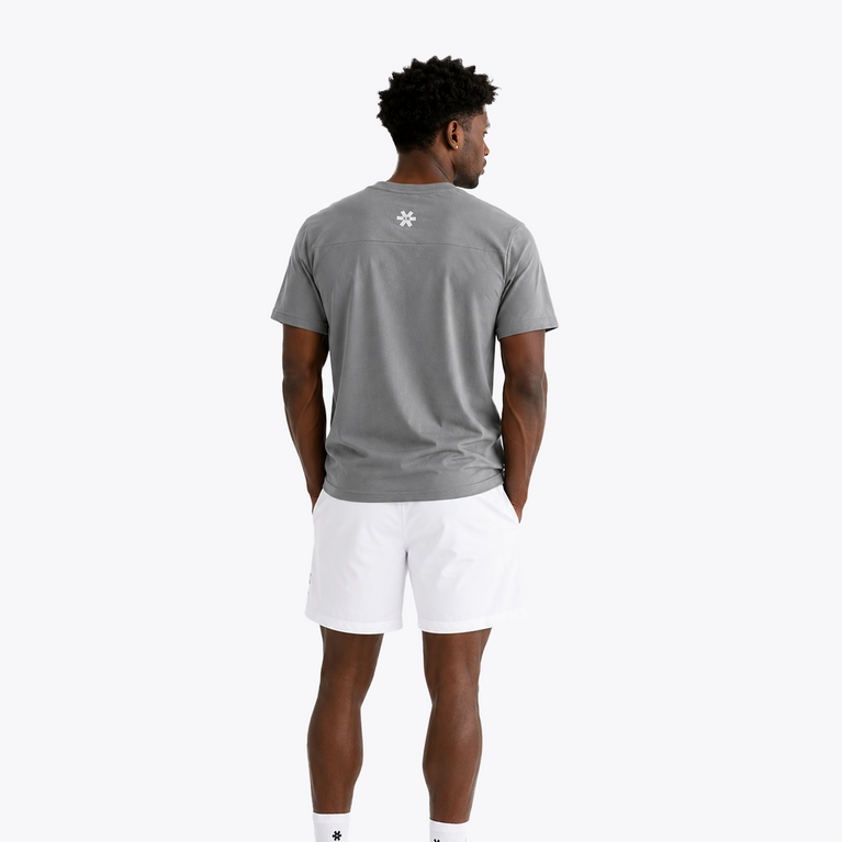 Black male model wearing Osaka Men’s Apex Training Tee in Quiet Gray with white training shorts, featuring reflective back logo and lightweight moisture-wicking performance fabric.