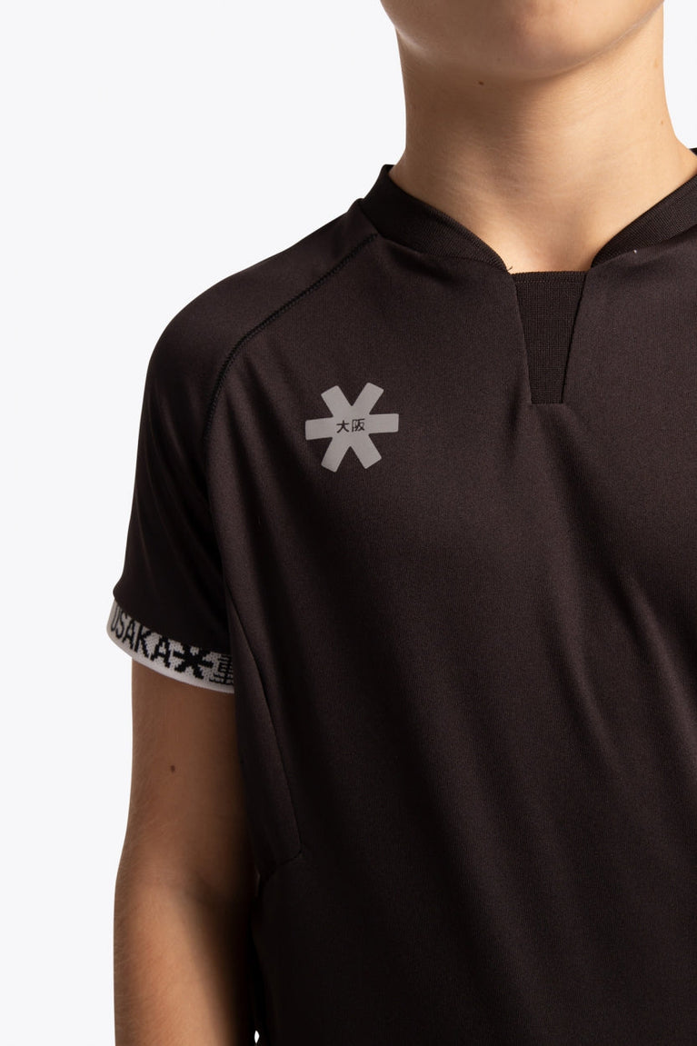 Boy wearing the Osaka Kids Jersey in Black. Front detail logoview