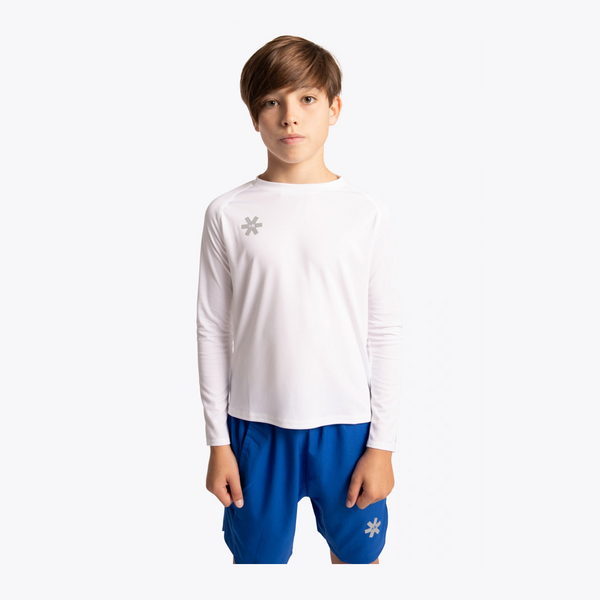 A young boy wearing a white long-sleeve athletic shirt with a small gray snowflake logo on the left chest, paired with royal blue shorts, against a plain white background. #White