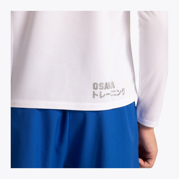 Close-up of a white athletic long-sleeve top with gray 'OSAIA トレーニング' text near the hem, worn with blue shorts against a light gray background. #White