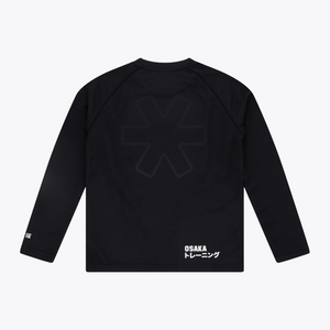 Black long-sleeve training top shown from the back, featuring a large tonal dark gray geometric logo on the upper back and white 'OSAKA トレーニング' text near the lower right hem, photographed on a light gray background. #Black