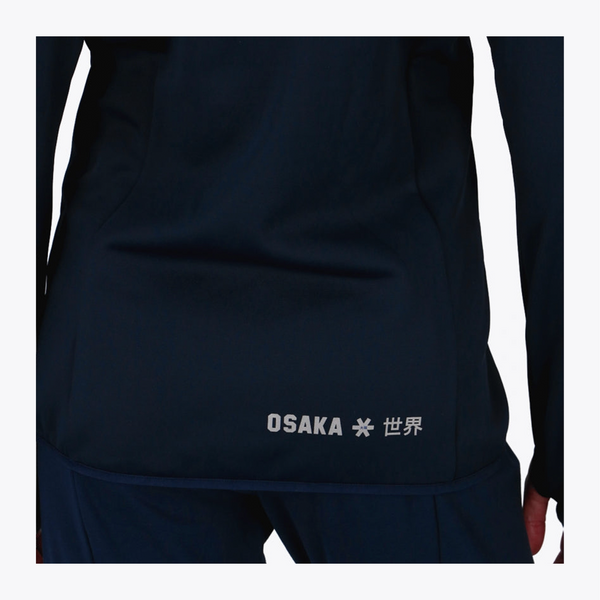Close-up of a dark navy athletic jacket or top with white 'OSAKA' text and a small star symbol near the lower front, shown on a person against a light gray background. #Navy