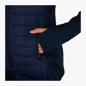 Close-up of a person wearing a dark navy quilted puffer vest, showing a hand reaching into a side zip pocket against a plain light background. #Navy