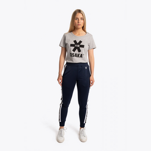 A woman modeling a light gray t-shirt with a black Osaka logo and navy blue jogger pants with white side stripes, paired with white sneakers, against a plain white background. #Navy