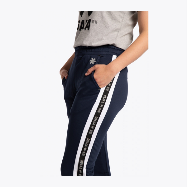 A person wearing navy blue athletic pants with a wide white side stripe featuring repeated black text, paired with a light gray cropped T-shirt, against a plain light background. #Navy