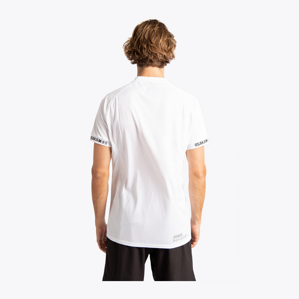 A man viewed from behind wearing a white short-sleeve athletic t-shirt with black text branding on the sleeve cuffs and lower hem, paired with black shorts, against a light gray studio background. #White