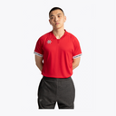 A man wearing a bright red short-sleeve athletic t-shirt with a small light blue flower logo on the left chest and white text on the cuffs, paired with dark gray sweatpants, against a plain white background. #Red